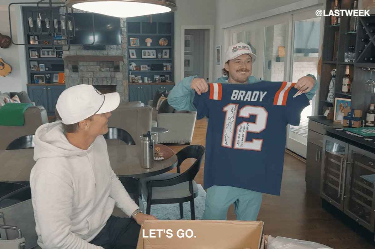 Morgan Wallen holding a signed Tom Brady football jersey